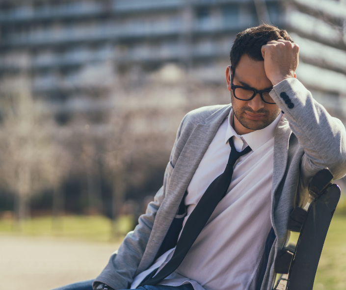 Image of man on bench looking dejected